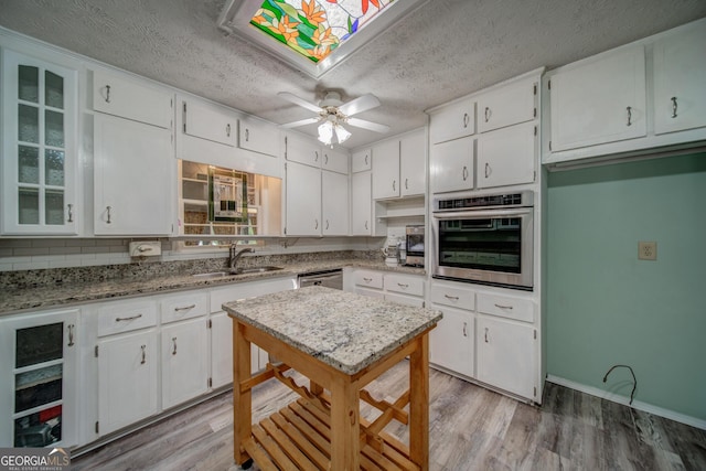 kitchen with appliances with stainless steel finishes, sink, white cabinets, and a textured ceiling