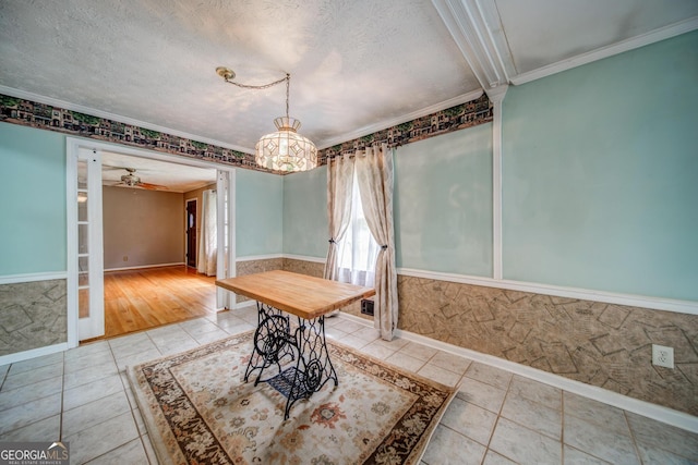 unfurnished dining area with tile patterned flooring, ceiling fan, ornamental molding, and a textured ceiling