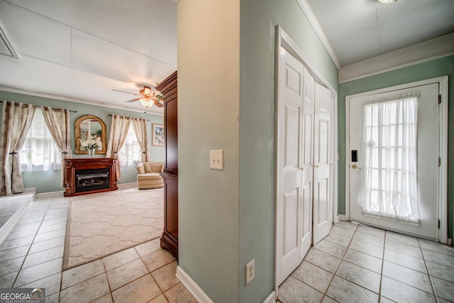 entryway featuring light tile patterned flooring, ceiling fan, ornamental molding, and a fireplace