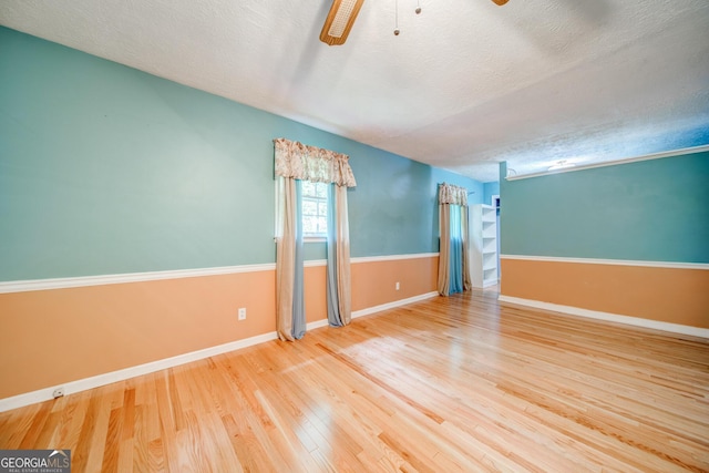 spare room featuring wood-type flooring, ceiling fan, and a textured ceiling