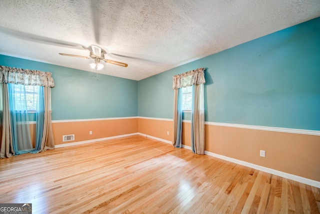 unfurnished room with a healthy amount of sunlight, wood-type flooring, and a textured ceiling