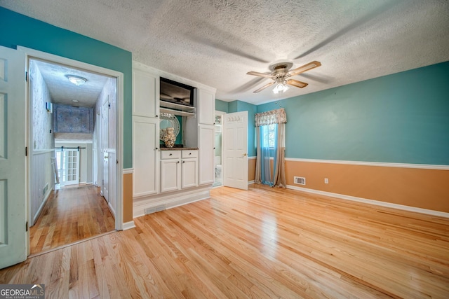 interior space featuring ceiling fan, light hardwood / wood-style floors, and a textured ceiling