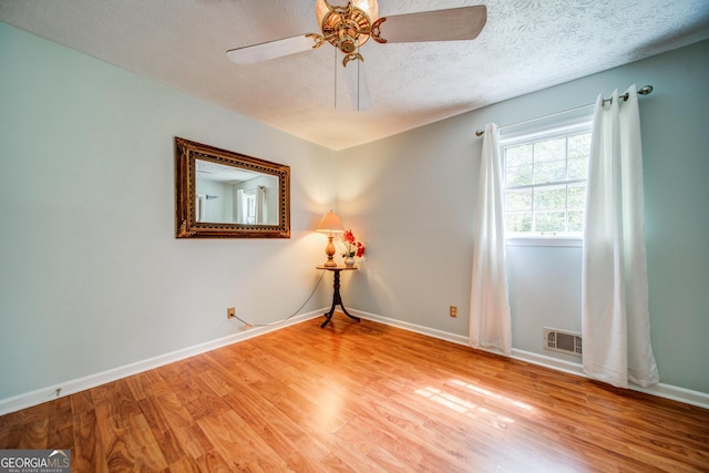 unfurnished room with ceiling fan, hardwood / wood-style floors, and a textured ceiling