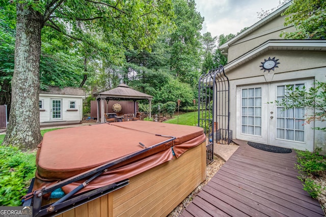 wooden deck featuring a gazebo, a hot tub, and an outbuilding