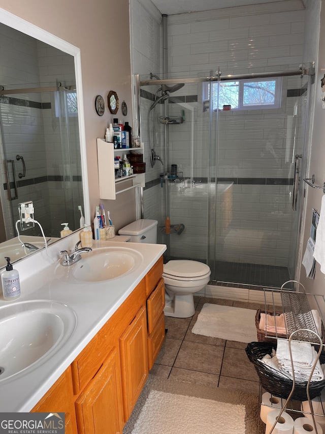 bathroom featuring tile patterned flooring, vanity, a shower with door, and toilet