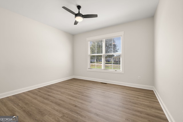 spare room with dark hardwood / wood-style flooring and ceiling fan