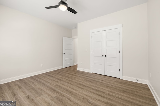 unfurnished bedroom featuring hardwood / wood-style floors, a closet, and ceiling fan