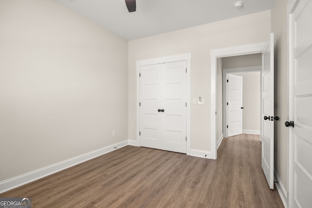 unfurnished bedroom with hardwood / wood-style flooring, ceiling fan, and a closet