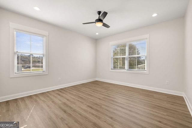 spare room featuring ceiling fan, wood-type flooring, and a healthy amount of sunlight