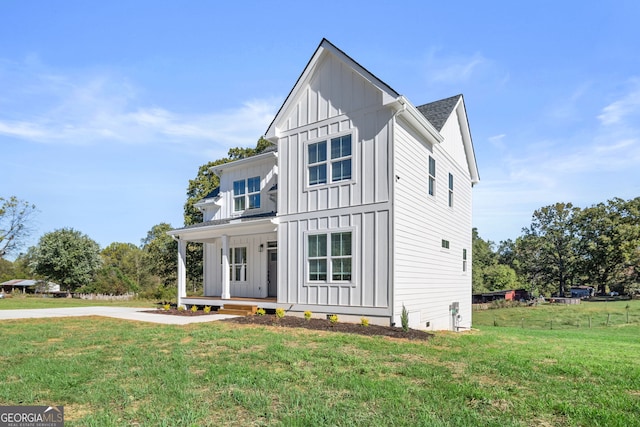 modern inspired farmhouse featuring covered porch and a front lawn