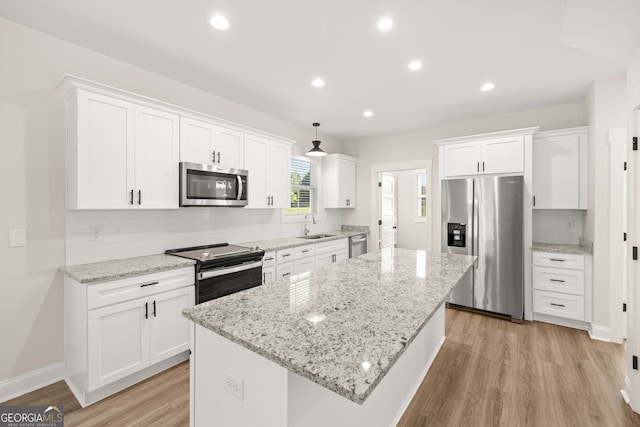 kitchen with sink, light wood-type flooring, appliances with stainless steel finishes, a kitchen island, and white cabinets