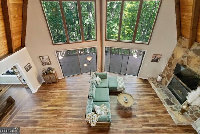 living room featuring a towering ceiling, a fireplace, and hardwood / wood-style flooring