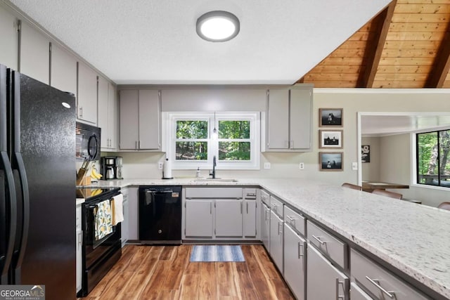 kitchen with gray cabinets, sink, vaulted ceiling with beams, black appliances, and wooden ceiling