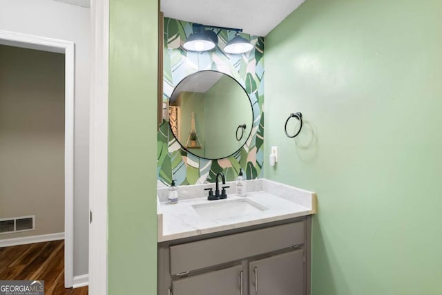 bathroom with hardwood / wood-style flooring, vanity, and a textured ceiling