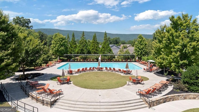 view of pool featuring a mountain view, a yard, and a patio