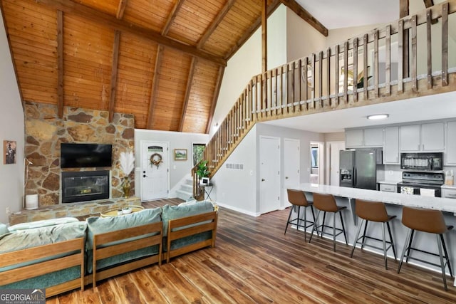 living room featuring dark wood-type flooring, beam ceiling, wood ceiling, high vaulted ceiling, and a fireplace