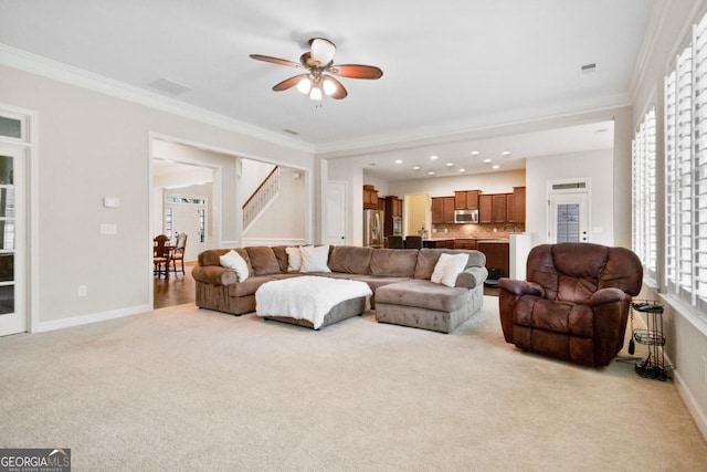 living room with light carpet, ornamental molding, and ceiling fan