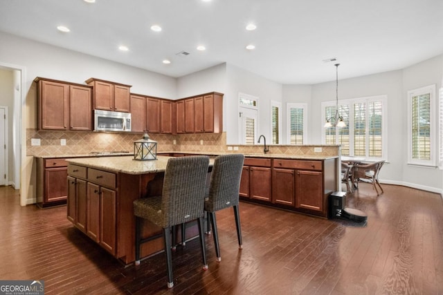 kitchen with a kitchen island, pendant lighting, sink, a breakfast bar area, and kitchen peninsula