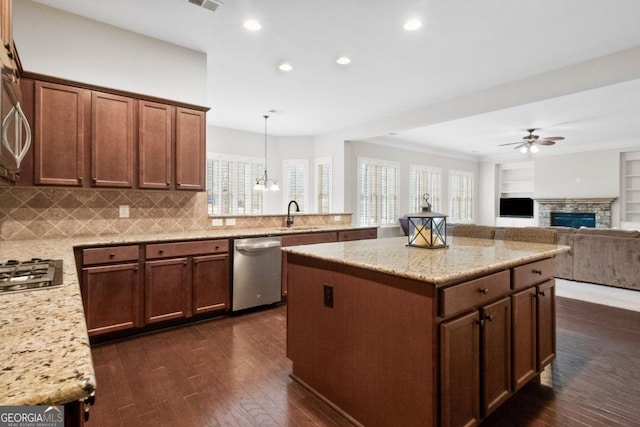 kitchen featuring sink, tasteful backsplash, hanging light fixtures, built in features, and stainless steel appliances