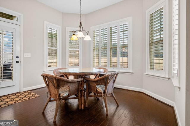 dining space with a healthy amount of sunlight, an inviting chandelier, and dark hardwood / wood-style flooring