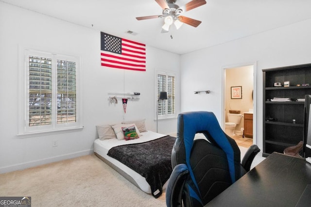 carpeted bedroom featuring multiple windows, ceiling fan, and ensuite bathroom