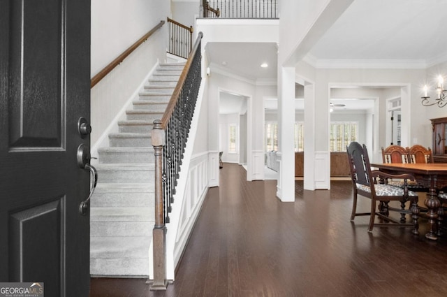 entryway with a notable chandelier, crown molding, and dark hardwood / wood-style floors