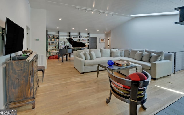 living room with rail lighting, lofted ceiling, and light wood-type flooring