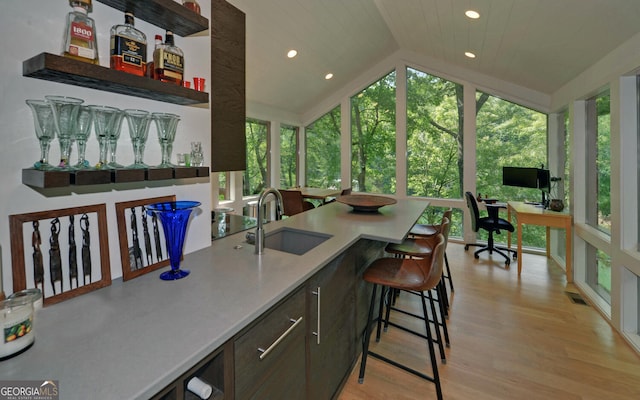 bar featuring lofted ceiling, sink, wood ceiling, dark brown cabinetry, and light hardwood / wood-style floors