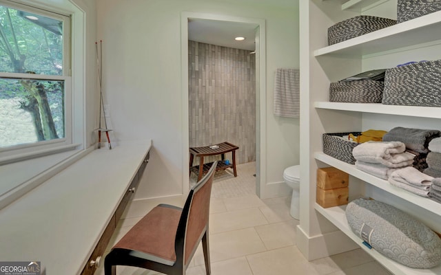 bathroom featuring a tile shower, a wealth of natural light, tile patterned floors, and toilet