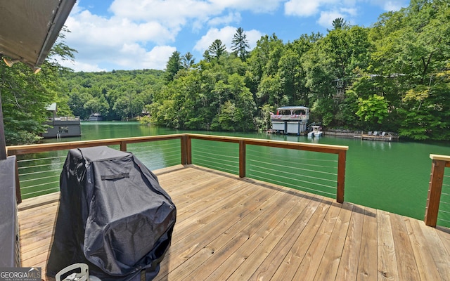 wooden deck with a water view and a grill