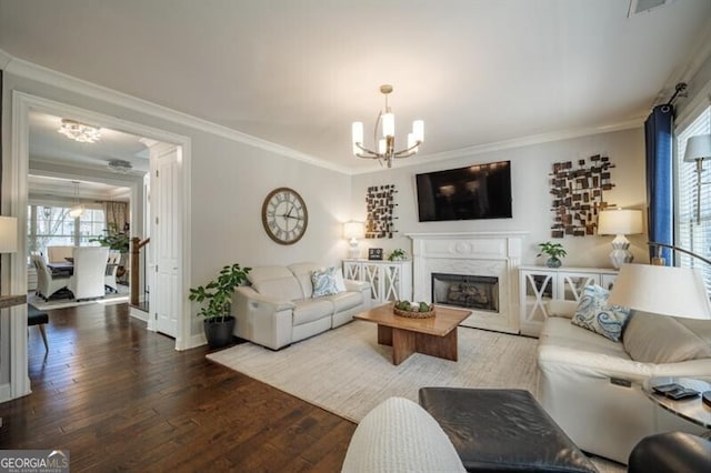 living room with crown molding, a fireplace, hardwood / wood-style floors, and a notable chandelier