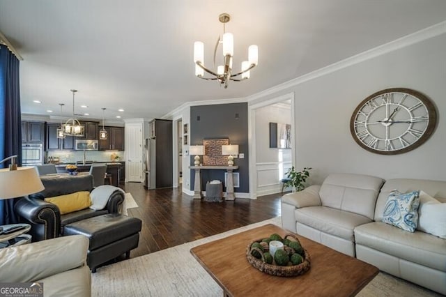 living room with an inviting chandelier, dark hardwood / wood-style floors, crown molding, and sink