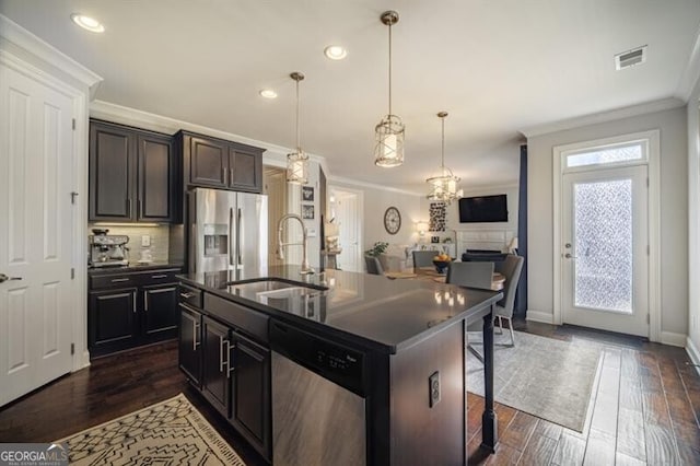 kitchen with appliances with stainless steel finishes, sink, a breakfast bar area, ornamental molding, and a kitchen island with sink