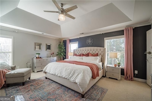 bedroom featuring a tray ceiling, ornamental molding, light colored carpet, and ceiling fan