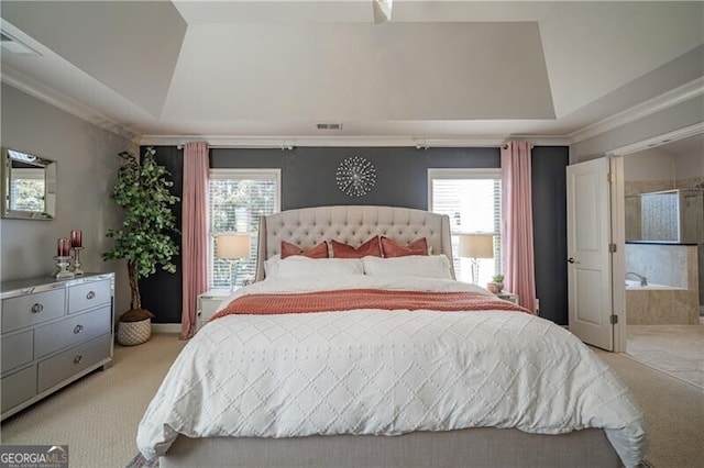 carpeted bedroom featuring ornamental molding, connected bathroom, and a tray ceiling