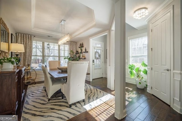 dining space with dark hardwood / wood-style flooring, a tray ceiling, and a chandelier