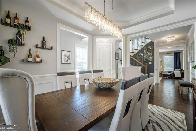 dining area with ornamental molding, dark wood-type flooring, a chandelier, and a tray ceiling