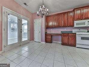 kitchen with french doors, white appliances, a chandelier, and light tile patterned floors