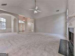 unfurnished living room with ceiling fan, carpet floors, and vaulted ceiling