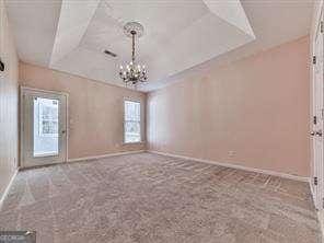 empty room featuring carpet and a notable chandelier