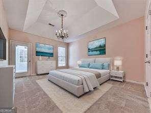 bedroom featuring multiple windows, a chandelier, and a tray ceiling