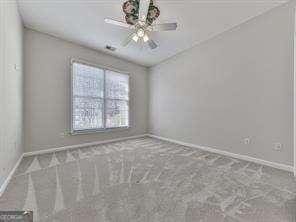 spare room featuring ceiling fan and carpet floors