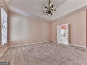 unfurnished room featuring a chandelier and carpet