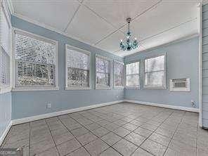 unfurnished sunroom featuring an AC wall unit and a chandelier