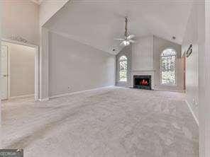 unfurnished living room featuring ceiling fan, lofted ceiling, and carpet