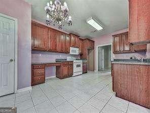 kitchen with white appliances, a chandelier, hanging light fixtures, and light tile patterned floors