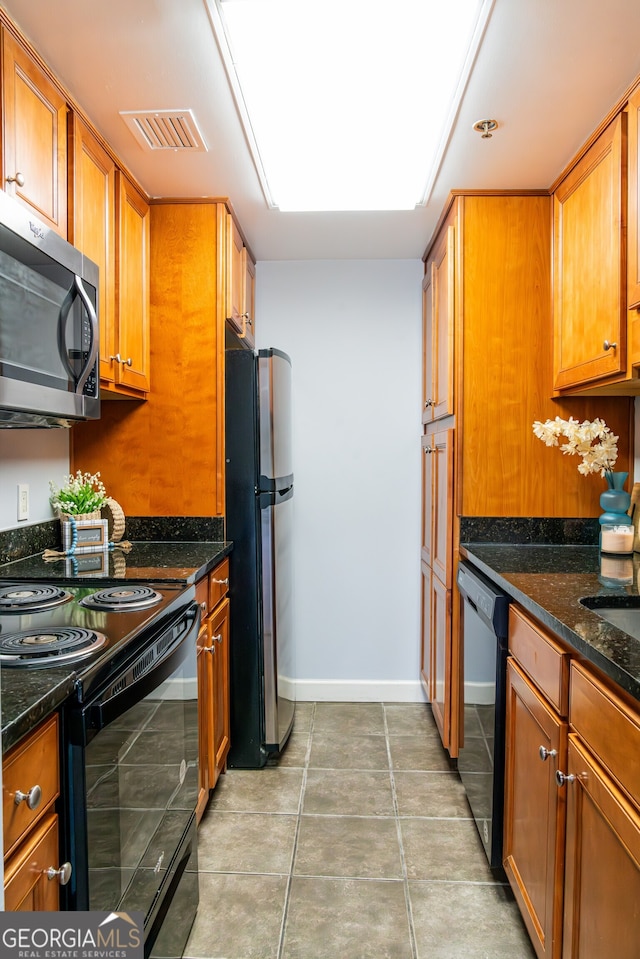 kitchen featuring tile patterned floors, dark stone counters, and black appliances