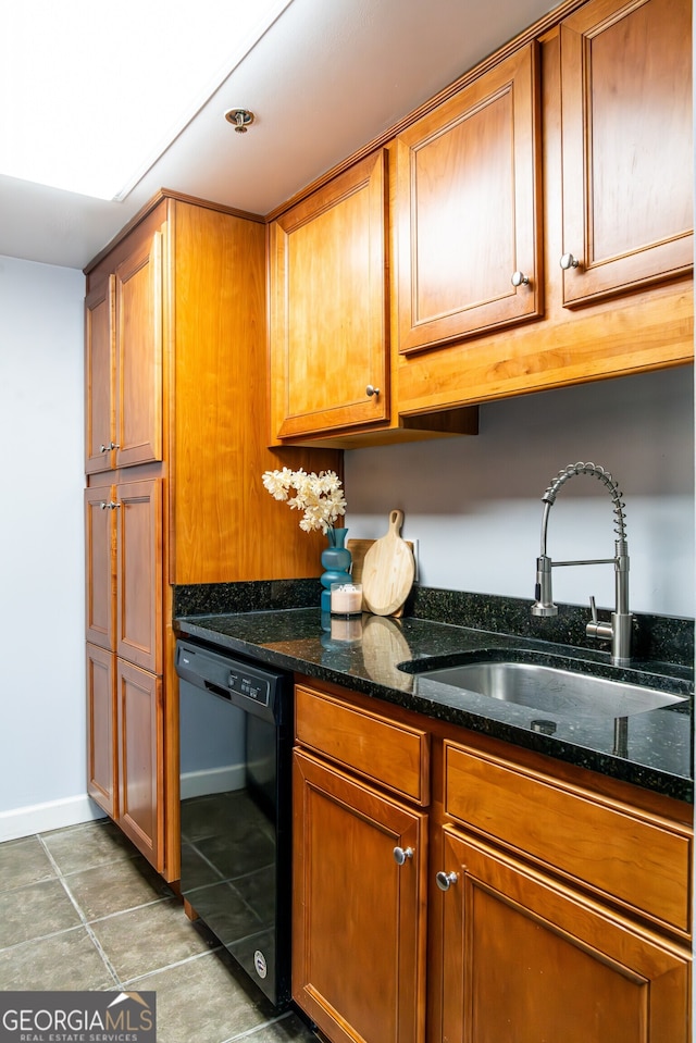 kitchen with dishwasher, sink, dark tile patterned flooring, and dark stone countertops