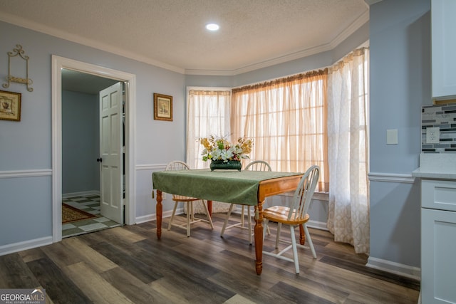 dining space with crown molding, dark wood-type flooring, and a textured ceiling