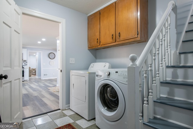 laundry area featuring washer and dryer, cabinets, and a textured ceiling